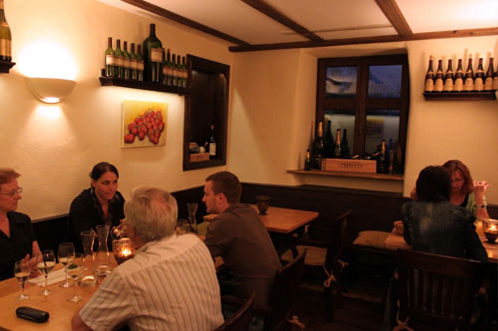 Gäste an gedeckten Tischen in der warm beleuchteten Weinstube der Hufschmiede